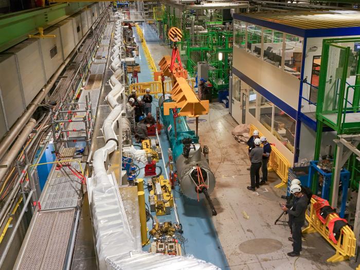 drone picture from above a teal cylindrical magnet being carried by a crane