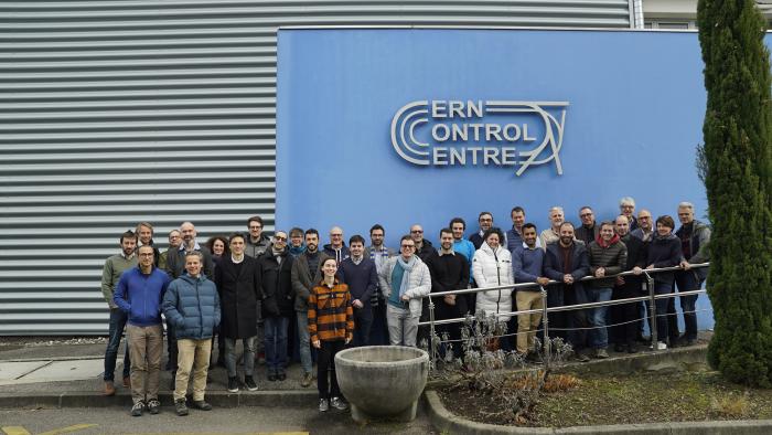 group picture of people smiling in front of a sign for the CERN Control Centre