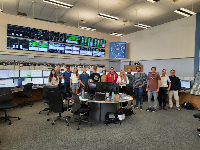 group picture in front of many screens showing different graphs and other data